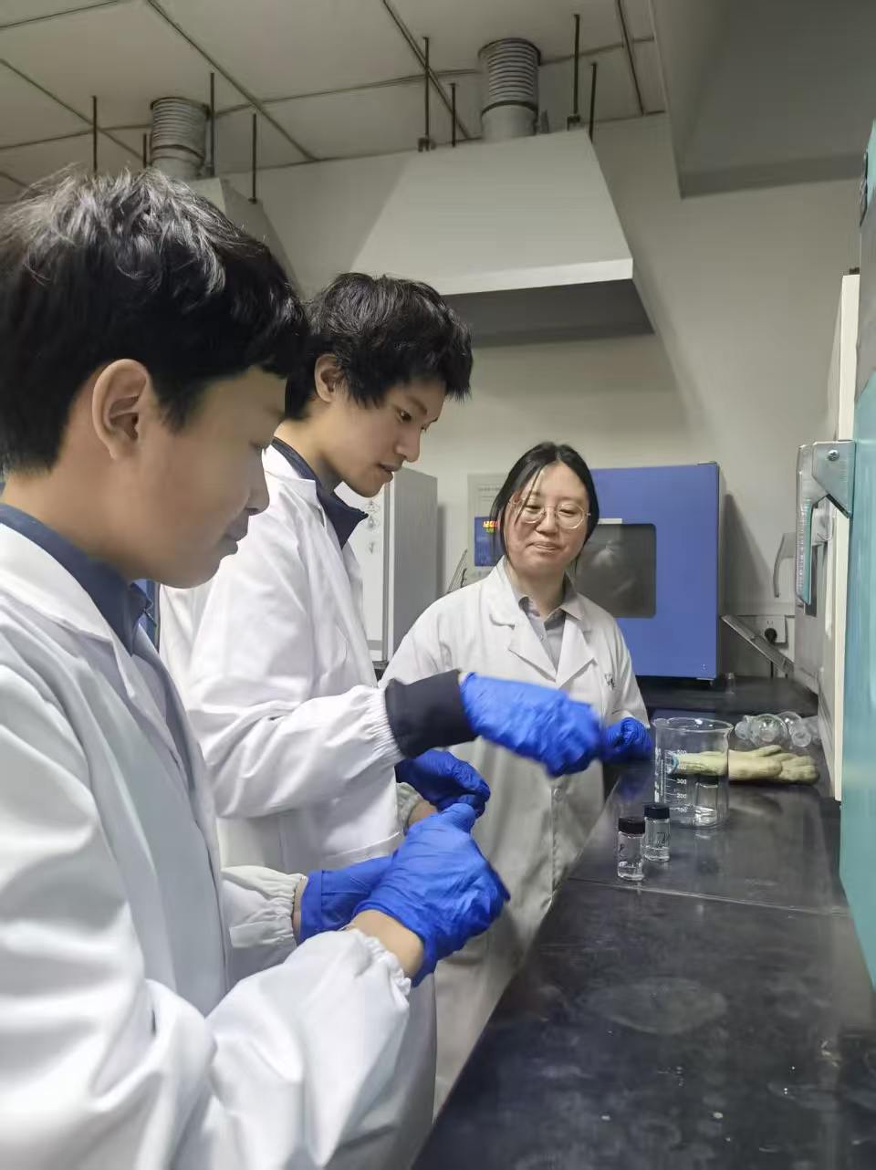 Daniel processing samples with lab partners under a fume hood