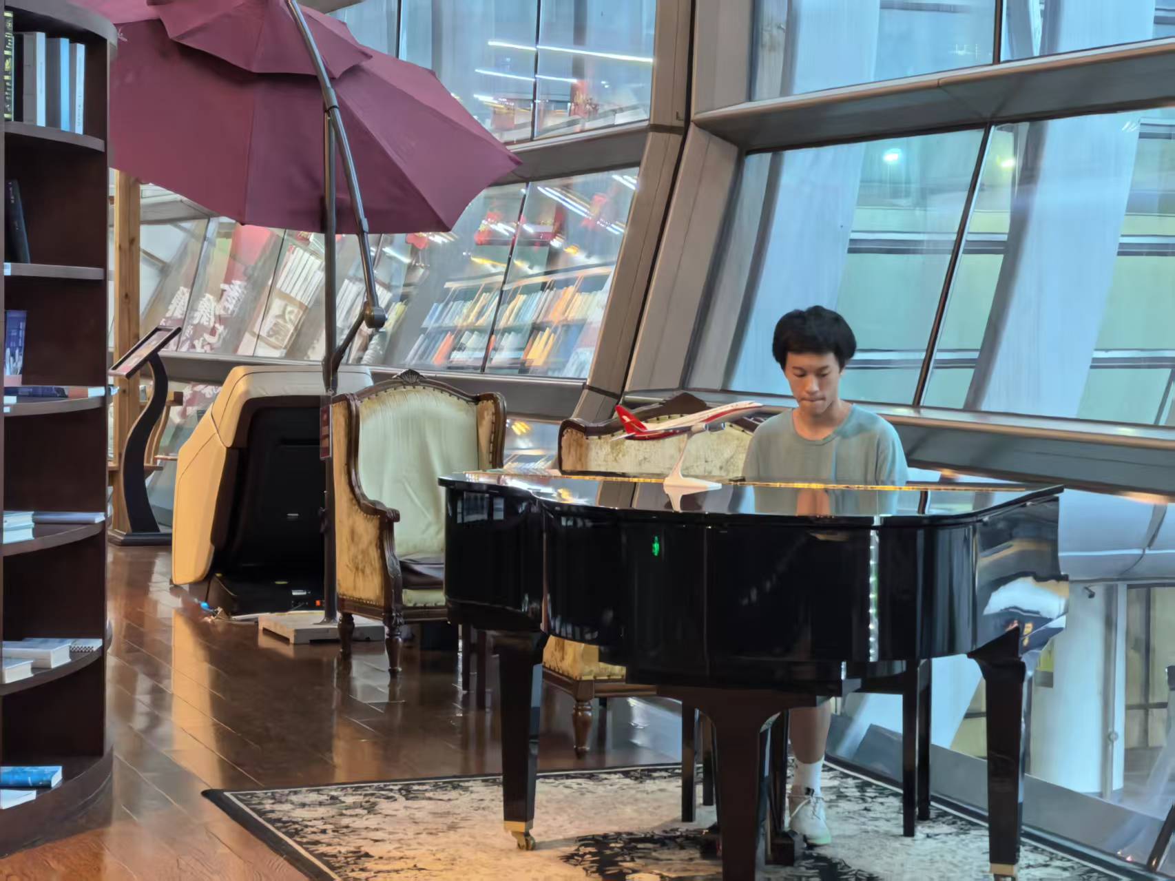 Daniel playing a grand piano between bookshelves